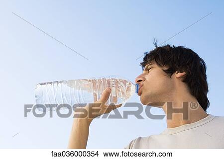 Man drinking large bottle of water, low angle view View Large Photo Image Picture - Man drinking large bottle of water, low angle view. Fotosearch