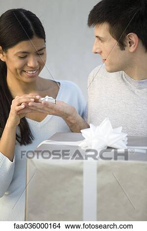 Picture - Man giving woman tiny gift, large gift in foreground. Fotosearch