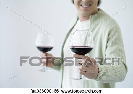 Man holding glass of wine, offering second glass to camera, cropped view View Large Photo Image Stock Photograph - Man holding glass of wine, offering second glass to camera, cropped view. Fotosearch
