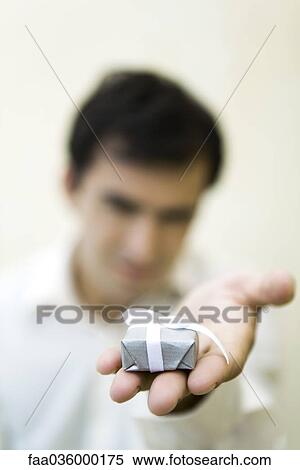 Man holding out small gift box, focus on foreground View Large Photo Image Stock Photography - Man holding out small gift box, focus on foreground. Fotosearch