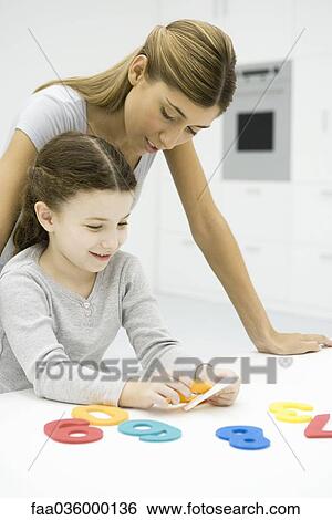 Mother and daughter looking at cut out numbers together View Large Photo Image Stock Photograph - Mother and daughter looking at cut out numbers together. Fotosearch