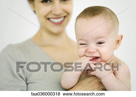 Mother holding infant, baby sticking hand in mouth, looking at camera View Large Photo Image Stock Photo - Mother holding infant, baby sticking hand in mouth, looking at camera. Fotosearch