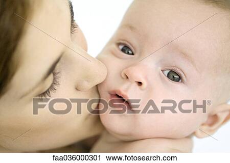 Mother kissing infant on the cheek, baby looking at camera View Large Photo Image Stock Image - Mother kissing infant on the cheek, baby looking at camera. Fotosearch