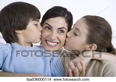 Portrait of smiling mother being kissed on each cheek by young daughter and son View Large Photo Image Picture - Portrait of smiling mother being kissed on each cheek by young daughter and son. Fotosearch