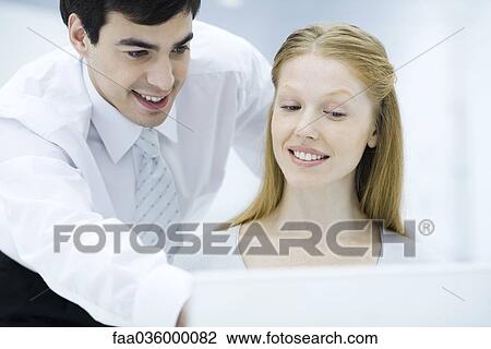 Professional man looking over female colleague's shoulder, pointing at laptop computer View Large Photo Image Stock Image - Professional man looking over female colleague's shoulder, pointing at laptop computer. Fotosearch