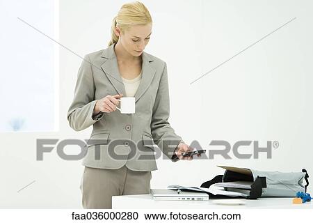 Professional woman holding coffee cup, looking down, text messaging View Large Photo Image Stock Image - Professional woman holding coffee cup, looking down, text messaging. Fotosearch