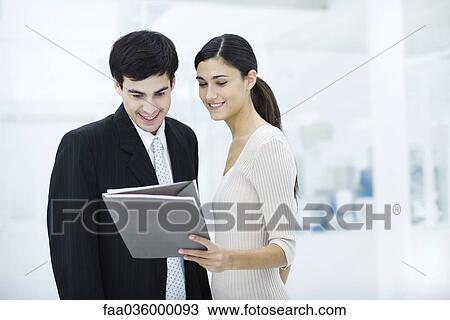 Professional woman showing male colleague document, both smiling View Large Photo Image Stock Image - Professional woman showing male colleague document, both smiling. Fotosearch