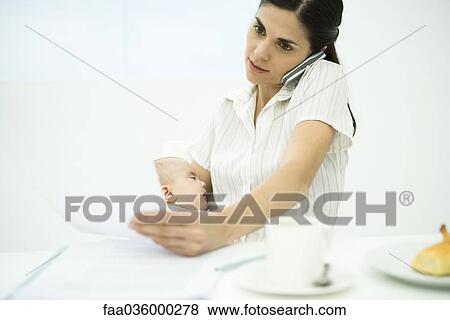 Professional woman using cell phone, holding baby, reviewing document View Large Photo Image Stock Photo - Professional woman using cell phone, holding baby, reviewing document. Fotosearch