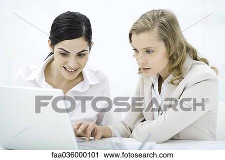 Professional women looking at laptop computer together, smiling View Large Photo Image Stock Image - Professional women looking at laptop computer together, smiling. Fotosearch