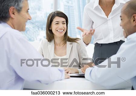 Professionals having a meeting at desk, focus on women in background View Large Photo Image Stock Image - Professionals having a meeting at desk, focus on women in background. Fotosearch