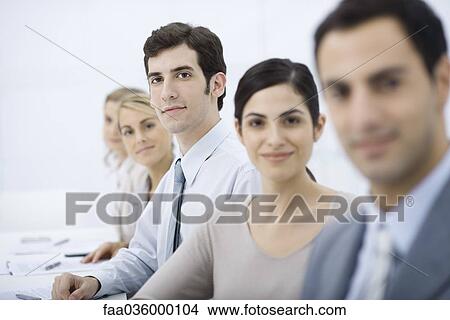 Picture - Professionals lined up, looking at camera, selective focus. Fotosearch