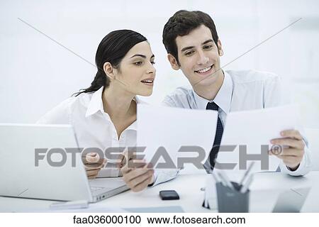 Professionals working together at desk, man holding documents View Large Photo Image Stock Image - Professionals working together at desk, man holding documents. Fotosearch