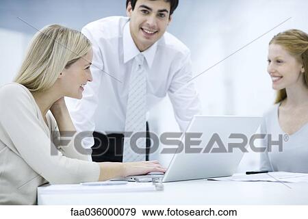 Professionals working with laptop computer together View Large Photo Image Stock Photo - Professionals working with laptop computer together. Fotosearch