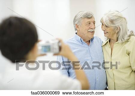 Senior couple being photographed by grandson, smiling at each other View Large Photo Image Stock Photo - Senior couple being photographed by grandson, smiling at each other. Fotosearch