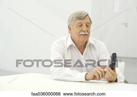 Stock Photo - Senior man using cell phone, smiling. Fotosearch
