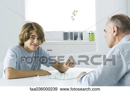 Teen boy playing chess with father, smiling at camera View Large Photo Image Stock Photo - Teen boy playing chess with father, smiling at camera. Fotosearch