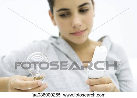 Teen girl comparing conventional lightbulb and energy efficient light bulb View Large Photo Image Stock Photography - Teen girl comparing conventional lightbulb and energy efficient light bulb. Fotosearch