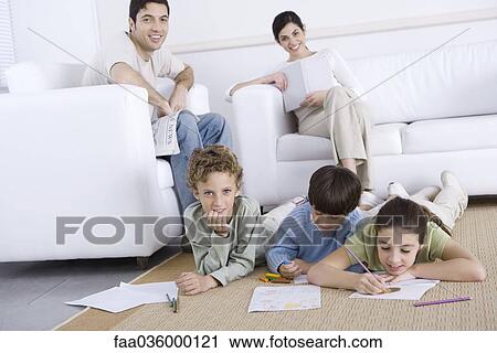 Three children coloring on the floor in living room, parents relaxing in background View Large Photo Image Stock Image - Three children coloring on the floor in living room, parents relaxing in background. Fotosearch