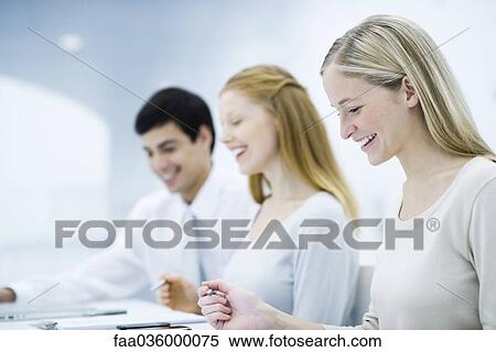 Three colleagues working at desk, smiling View Large Photo Image Stock Photography - Three colleagues working at desk, smiling. Fotosearch