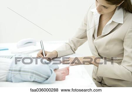 Woman editing document at desk, infant lying nearby, cropped view View Large Photo Image Stock Photo - Woman editing document at desk, infant lying nearby, cropped view. Fotosearch