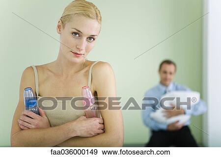 Woman holding baby bottles, smiling at camera, husband holding baby in background View Large Photo Image Stock Photo - Woman holding baby bottles, smiling at camera, husband holding baby in background. Fotosearch