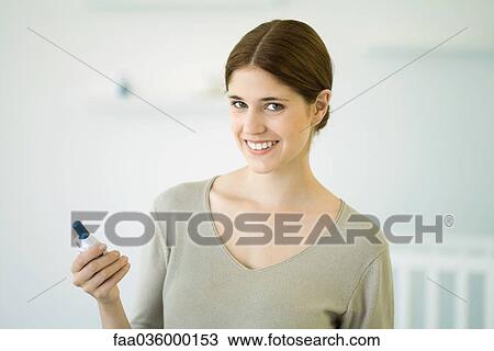 Woman holding baby monitor, smiling at camera View Large Photo Image Stock Image - Woman holding baby monitor, smiling at camera. Fotosearch