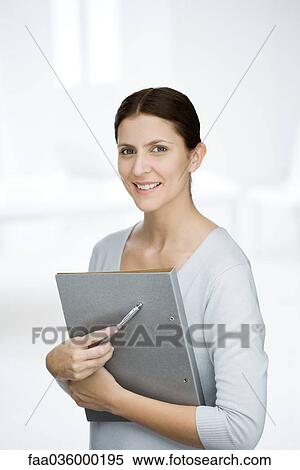 Woman holding folder, smiling at camera, portrait View Large Photo Image Stock Photography - Woman holding folder, smiling at camera, portrait. Fotosearch
