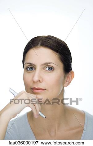Stock Photo - Woman holding pen, looking at camera, portrait. Fotosearch