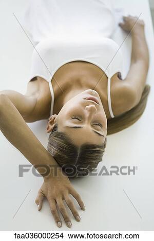 Woman lying on back, eyes closed, high angle view View Large Photo Image Picture - Woman lying on back, eyes closed, high angle view. Fotosearch