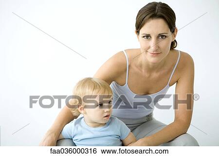Woman smiling at camera, toddler standing between legs View Large Photo Image Stock Photograph - Woman smiling at camera, toddler standing between legs. Fotosearch