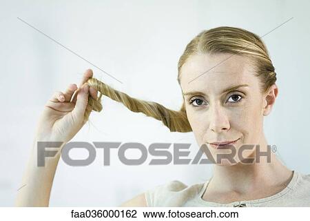 Woman twisting hair, smiling at camera, portrait View Large Photo Image Stock Image - Woman twisting hair, smiling at camera, portrait. Fotosearch