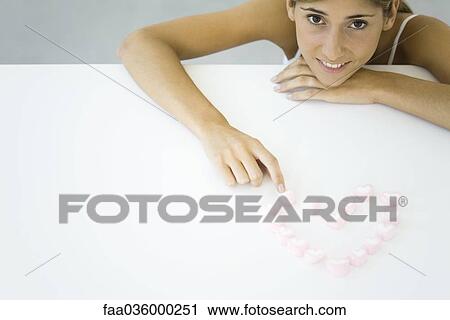 Woman with candy hearts arranged in heart shape, resting chin on hand, smiling at camera View Large Photo Image Stock Image - Woman with candy hearts arranged in heart shape, resting chin on hand, smiling at camera. Fotosearch