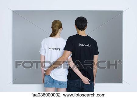 Young couple wearing customized tee-shirts, arms around each other's waists, rear view View Large Photo Image Stock Image - Young couple wearing customized tee-shirts, arms around each other's waists, rear view. Fotosearch