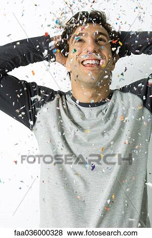 Young man amidst falling confetti, laughing, hands behind head View Large Photo Image Stock Photo - Young man amidst falling confetti, laughing, hands behind head. Fotosearch