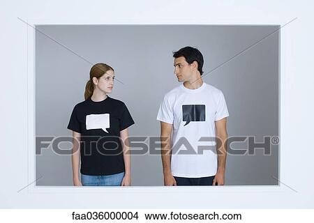 Picture - Young man and young woman wearing tee-shirts printed with blank word bubbles, looking at each other. Fotosearch