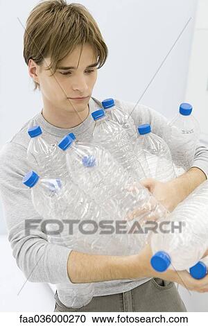 Young man carrying armful of plastic bottles View Large Photo Image Stock Image - Young man carrying armful of plastic bottles. Fotosearch