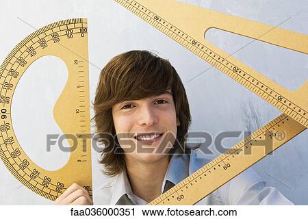 Young man holding various measuring instruments, smiling at camera View Large Photo Image Stock Image - Young man holding various measuring instruments, smiling at camera. Fotosearch