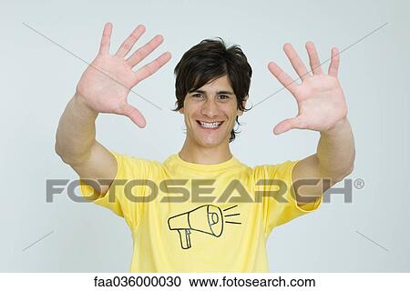 Young man wearing tee-shirt with megaphone graphic, smiling at camera, hands raised View Large Photo Image Stock Image - Young man wearing tee-shirt with megaphone graphic, smiling at camera, hands raised. Fotosearch