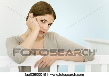 Young mother leaning against crib, looking at camera View Large Photo Image Stock Image - Young mother leaning against crib, looking at camera. Fotosearch