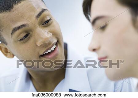 Stock Photo - Young professional man chatting with colleague, smiling. Fotosearch