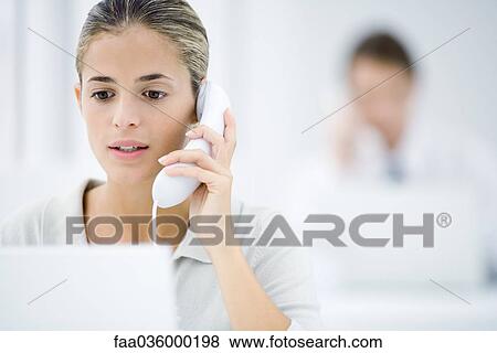 Young woman in office, using landline phone View Large Photo Image Stock Photo - Young woman in office, using landline phone. Fotosearch