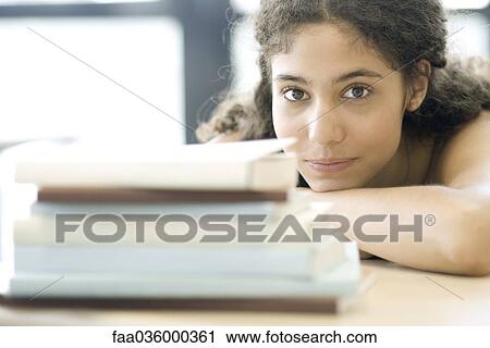 Young woman resting head on arms, behind pile of books View Large Photo Image Stock Image - Young woman resting head on arms, behind pile of books. Fotosearch
