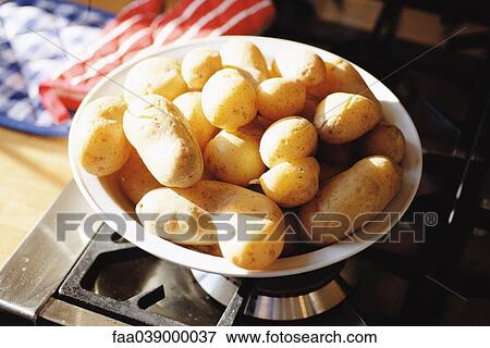 Stock Photo - Bowl of potatoes on stove. Fotosearch