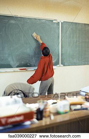 Boy erasing blackboard in classroom View Large Photo Image Stock Photo - Boy erasing blackboard in classroom. Fotosearch