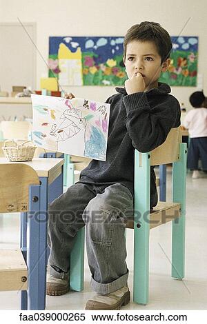 Boy holding up drawing in class room View Large Photo Image Stock Photography - Boy holding up drawing in class room. Fotosearch