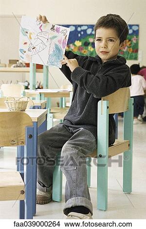 Picture - Boy showing drawing in class room. Fotosearch