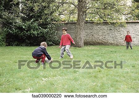 Stock Image - Boys playing with ball in yard. Fotosearch