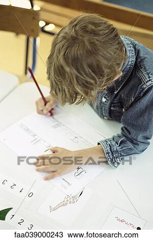 Stock Image - Child working on handwriting exercise, high angle view. Fotosearch