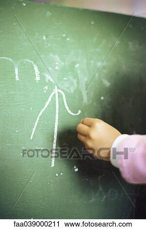 Stock Image - Child's hand writing on chalk board. Fotosearch