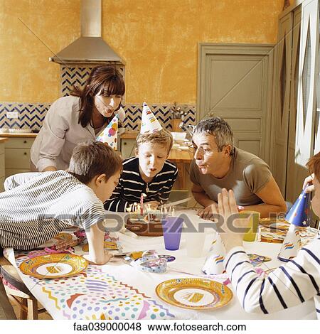 Stock Photo - Family blowing out candles on birthday cake. Fotosearch